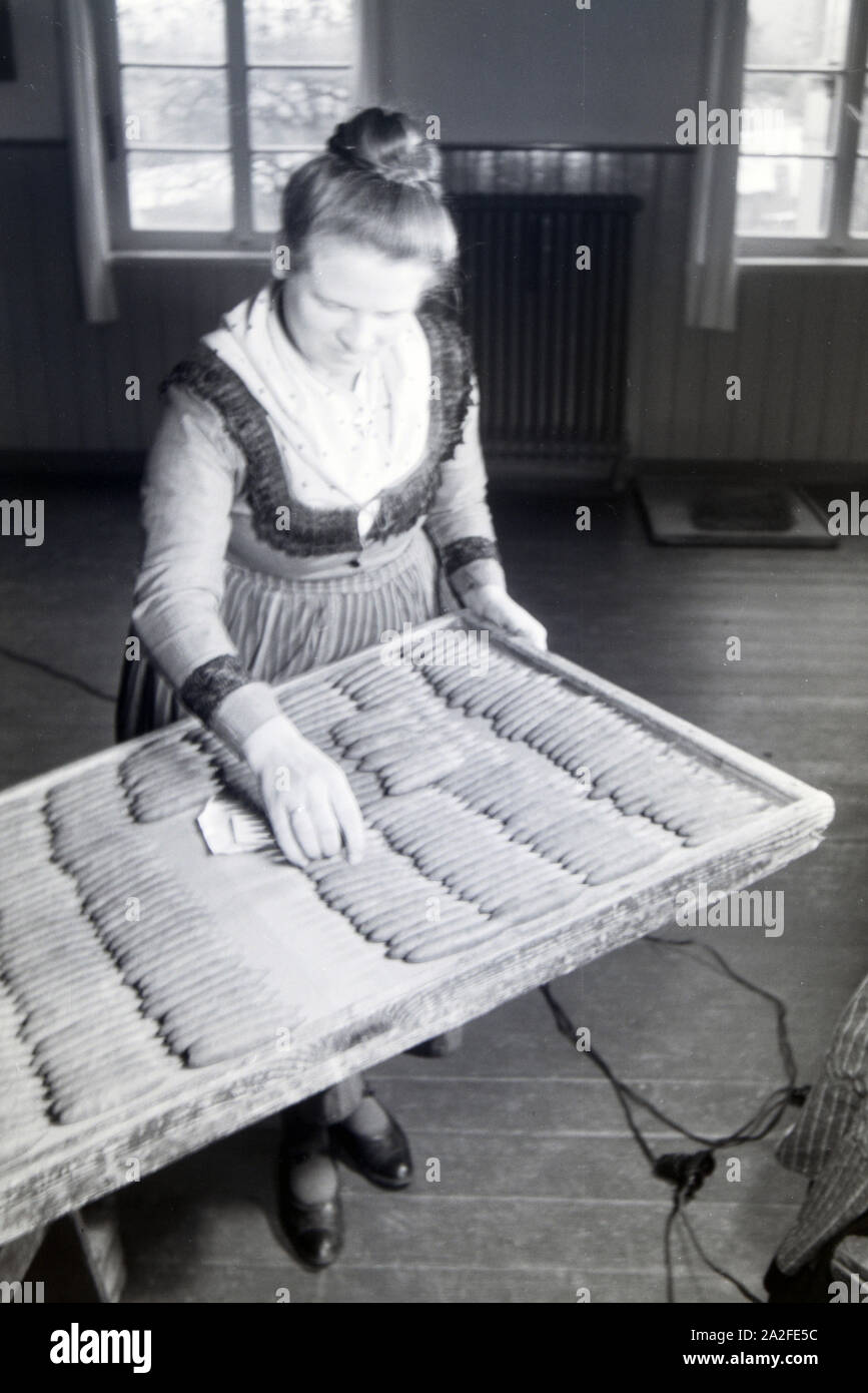 Eine Zigarrenrollerin in Marburger Tracht zählt die fertigen handgerollten Zigarren ab, sterben in einem großen Holztablett sortiert sind, bei Marburg, Deutschland 1930er Jahre. Eine weibliche Zigarrerolle Tragen eines Marburg Gewandung/Kostüm ist zählen die fertigen handgerollte Zigarren, die auf einen großen hölzernen Platte sortiert sind, in der Nähe von Marburg, Deutschland 1930. Stockfoto