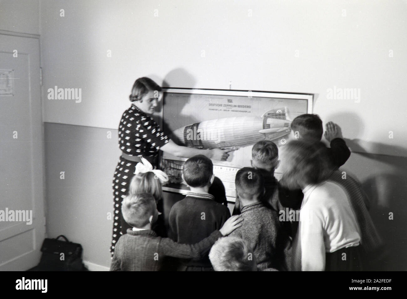 Eine Schulklasse lässt sich mit großem Interesse von ihrer Lehrerin den Aufbau eines Zeppeline erklären, Zeppelin Siedlung bei Frankfurt am Main, Deutschland 1930er. Ein Lehrer erklärt den Bau einer zeppelinl zu ihrer Schüler, die Hören mit großem Interesse sind, zeppelin Dorf in der Nähe von Frankfurt am Main, Deutschland 1930. Stockfoto
