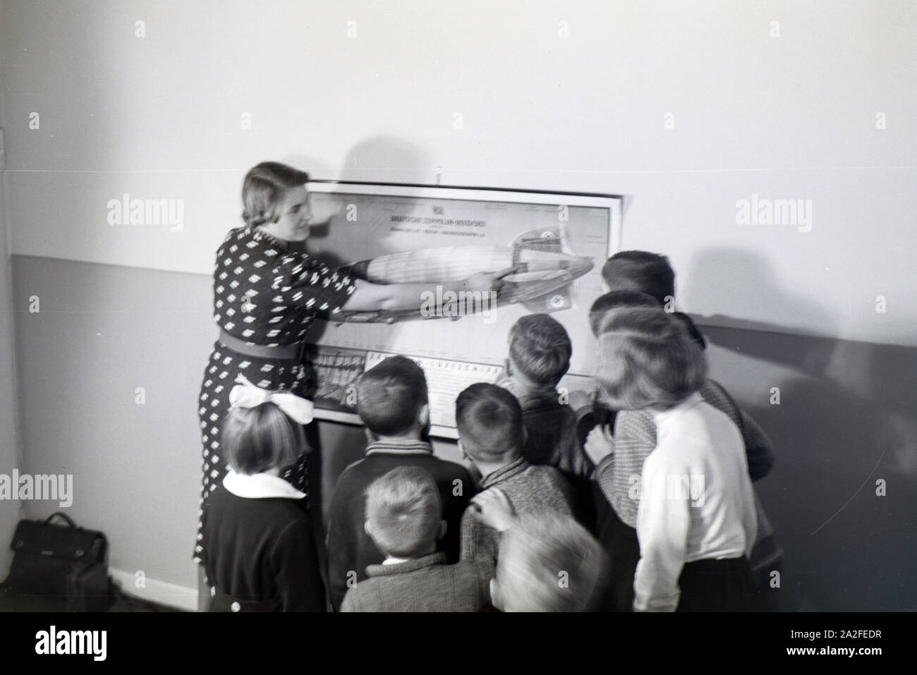 Eine Schulklasse lässt sich mit großem Interesse von ihrer Lehrerin den Aufbau eines Zeppeline erklären, Zeppelin Siedlung bei Frankfurt am Main, Deutschland 1930er. Ein Lehrer erklärt den Bau einer zeppelinl zu ihrer Schüler, die Hören mit großem Interesse sind, zeppelin Dorf in der Nähe von Frankfurt am Main, Deutschland 1930. Stockfoto