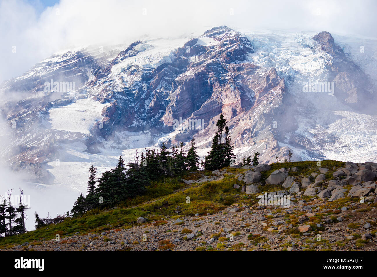 Mt. Rainier beginnend in Nebel an einem sonnigen Tag mit der rauen Landschaft im Staat Washington ummantelt werden Stockfoto