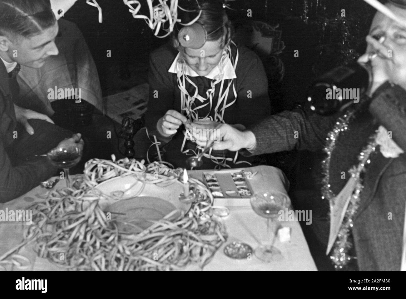 Zwei Männer und eine Frau beim Bleigießen in einer Silversterfeier, Deutschland 1930er Jahre. Zwei Männer und eine Frau dabei molybdomancy an eine Silvesterparty, Deutschland 1930. Stockfoto