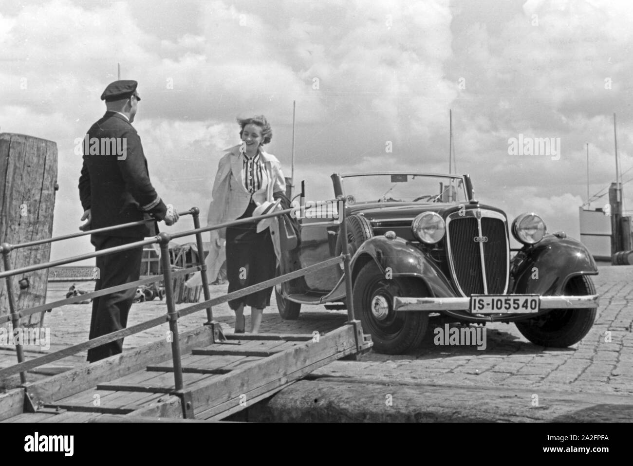 Eine Frau begrüßt einen Seemann an der Gangway in Norddeich Mole vor ihrem Audi Cabrio, Deutschland 1930er Jahre. Eine Frau und ein Seemann die Hände schütteln über einen Gang vor ein Audi Cabrio, Deutschland 1930. Stockfoto