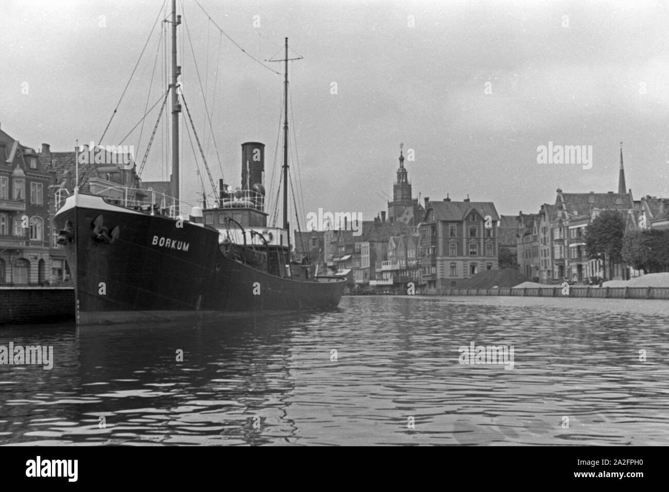 Das Schiff "Borkum" im Hafen von Emden mit Blick in das Emder Rathaus, Deutschland 1930er Jahre. Schiff "Borkum" im Emder Hafen mit Blick auf die Stadt und die Stadt Halle, Deutschland 1930. Stockfoto