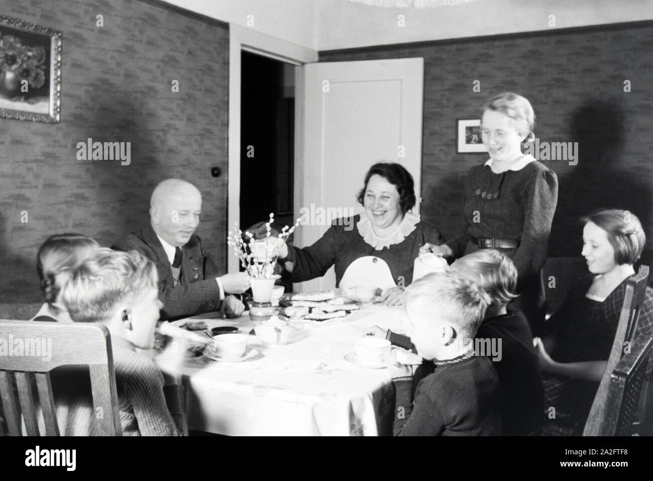 Mitglieder einer kinderreichen Familie bei Kaffe und Kuchen, Deutsches Reich 30er Jahre. Mitglieder einer Großfamilie mit Kaffee und Kuchen, Germa Stockfoto