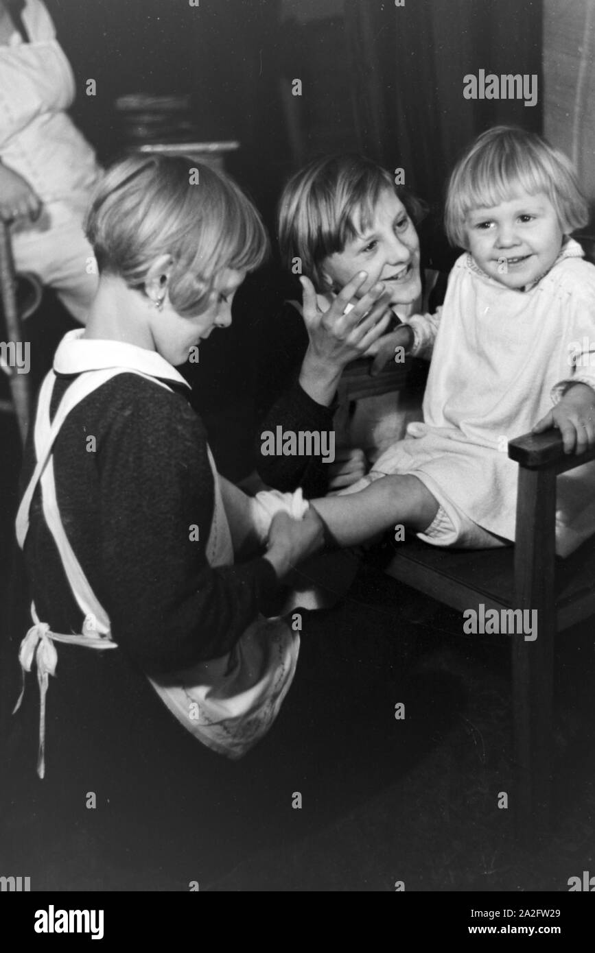 Zwei der Vierlinge von Brücken kümmern sich um Ihr jüngstes Geschwisterkind, Deutsches Reich 30er Jahre. Zwei der vierlinge von Brücken auf der Suche nach ihrer jüngsten Geschwister, Deutschland 1930. Stockfoto