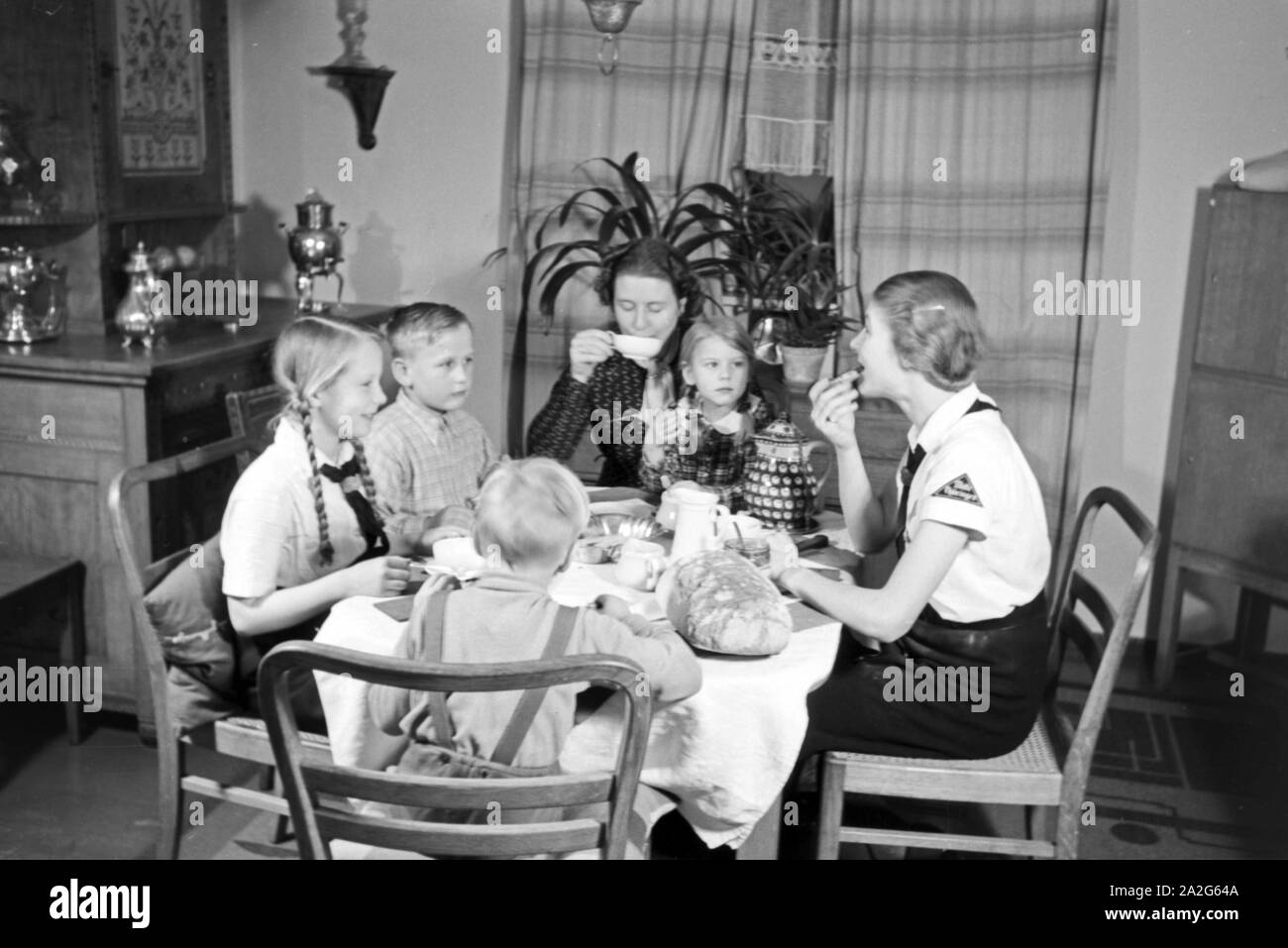 Eine Mutter sitzt mit fünf Kinder beim Frühstück am Küchentisch, Deutschland 1930er Jahre. Eine Mutter und ihre fünf Kinder mit Frühstück in der Küche, Deutschland 1930. Stockfoto