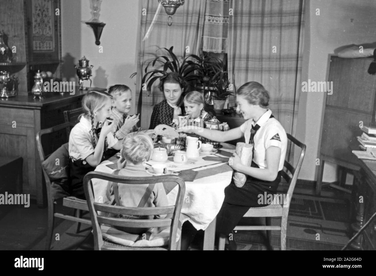 Eine Mutter sitzt mit fünf Kinder beim Frühstück am Küchentisch, Deutschland 1930er Jahre. Eine Mutter und ihre fünf Kinder mit Frühstück in der Küche, Deutschland 1930. Stockfoto