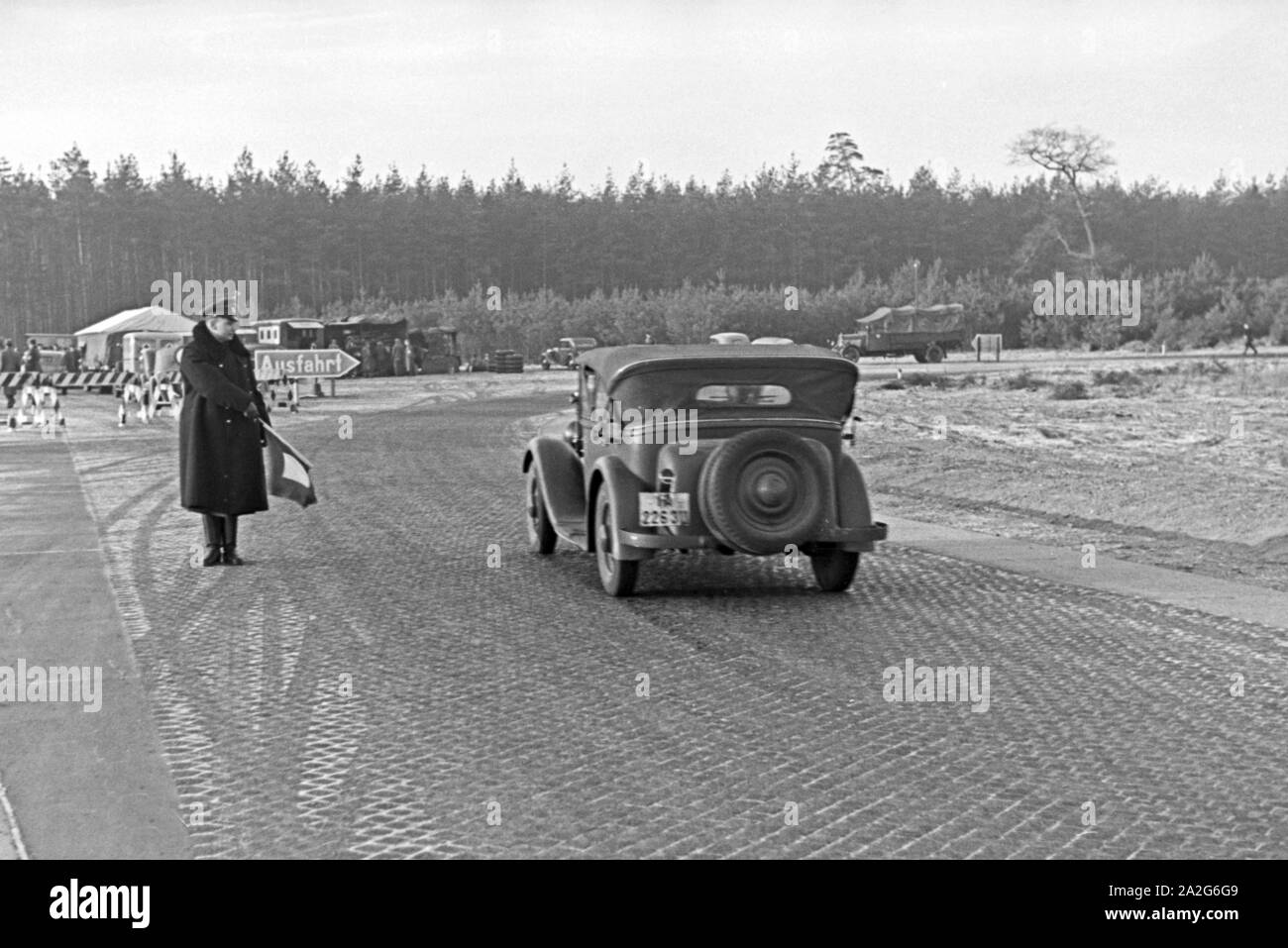 Ein verkehrsposten leitet den Zivilverkehr um für den Weltrekordversuch mit dem Mercedes Benz W 125, Deutschland 1930er Jahre. Ein Polizist unter Umgehung der zivilen Verkehr für den Weltrekord Versuch mit der Mercedes Benz W 125, Deutschland 1930. Stockfoto