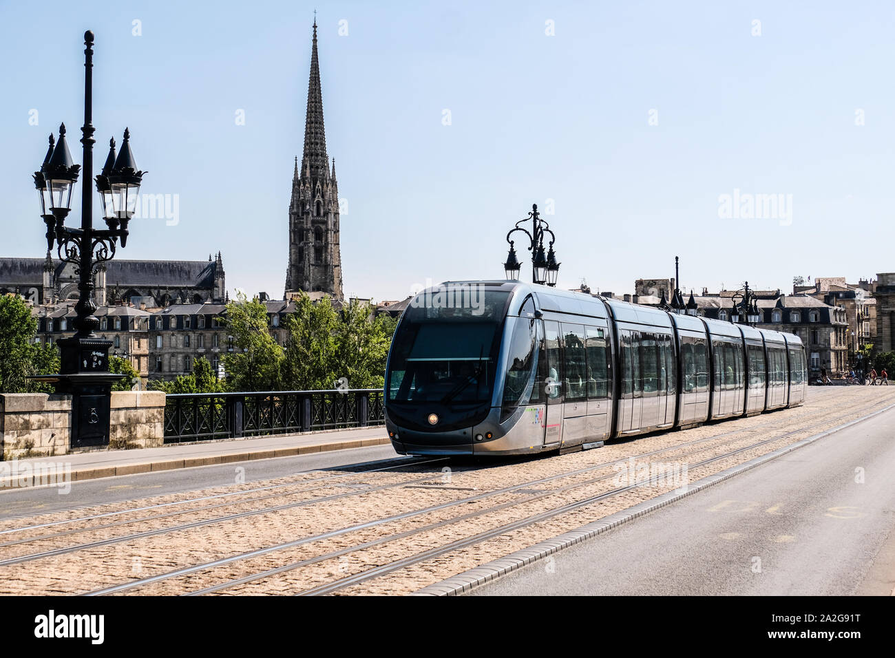 Eine öffentliche verkehrsmittel Straßenbahn fährt auf Pont de Pierre in Bordeaux, Frankreich, mit Basilique Saint Michel Kathedrale im Hintergrund Stockfoto