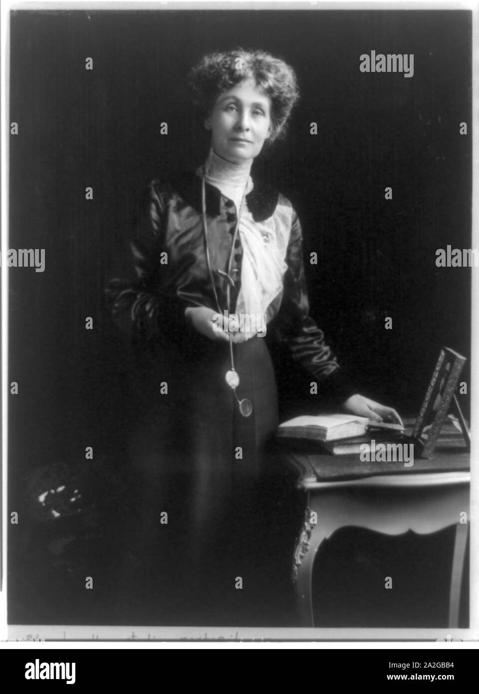 Emmeline Pankhurst (goulden), drei-viertel länge Portrait, kleiner Tisch, gegenüber der Rechten, mit der linken Hand auf dem Buch Stockfoto