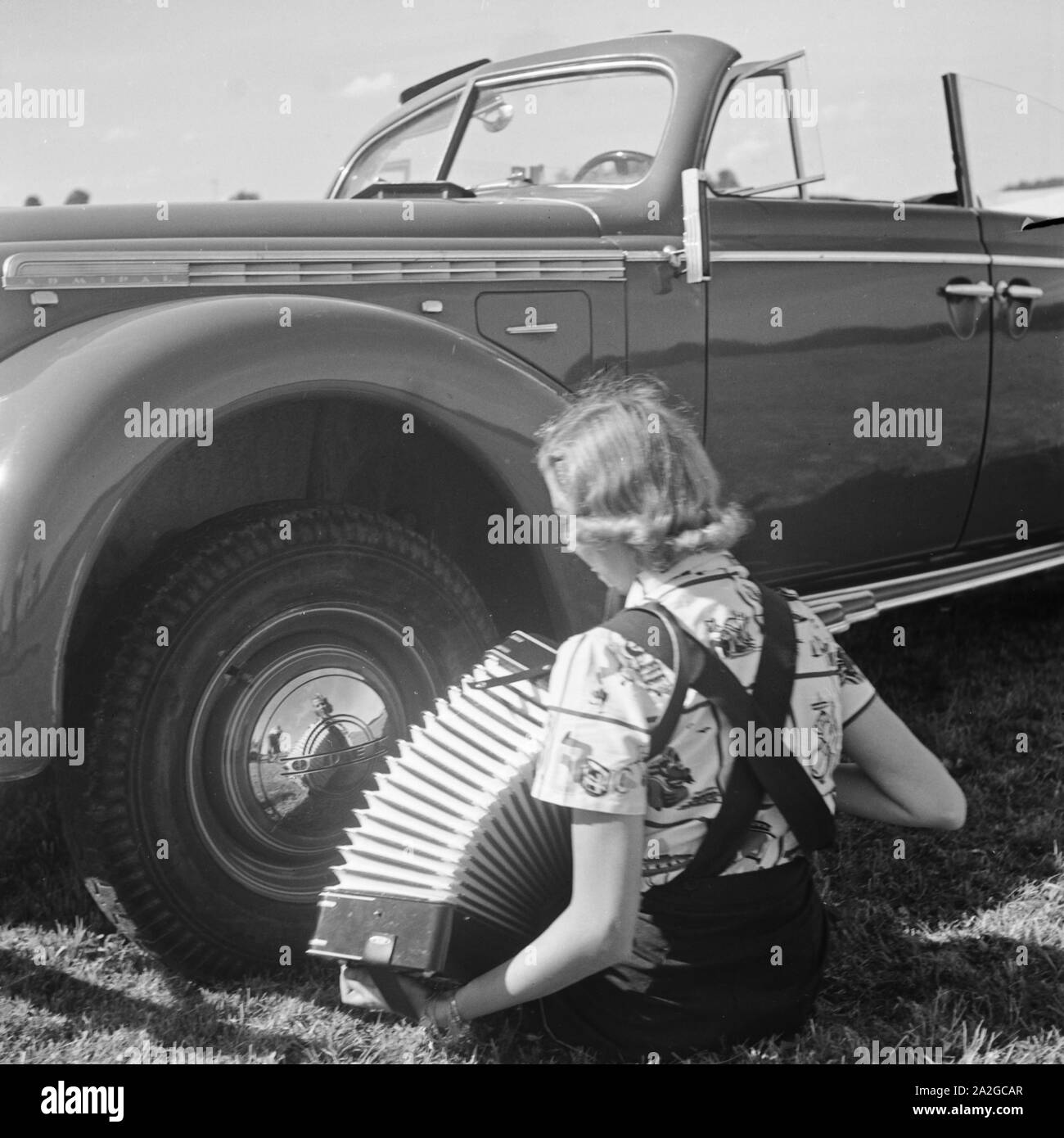 Eine Junge Frau Mit Einem Akkordeon Vor Einem Opel Admiral, 1930er Jahre Deutschland. Eine junge Frau, die durch ein Opel-Modell Admiral, Deutschland 1930er Jahren Akkordeon zu spielen. Stockfoto