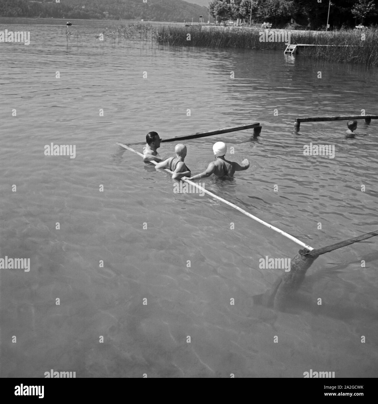 Badende in einem Nichtschwimmer- und Wohlfühlbereich ein Einems Ufer eines sieht in Österreich, 1930er Jahre. Baden entspannen Sie am Eingang zu einem See in Österreich, 1930. Stockfoto