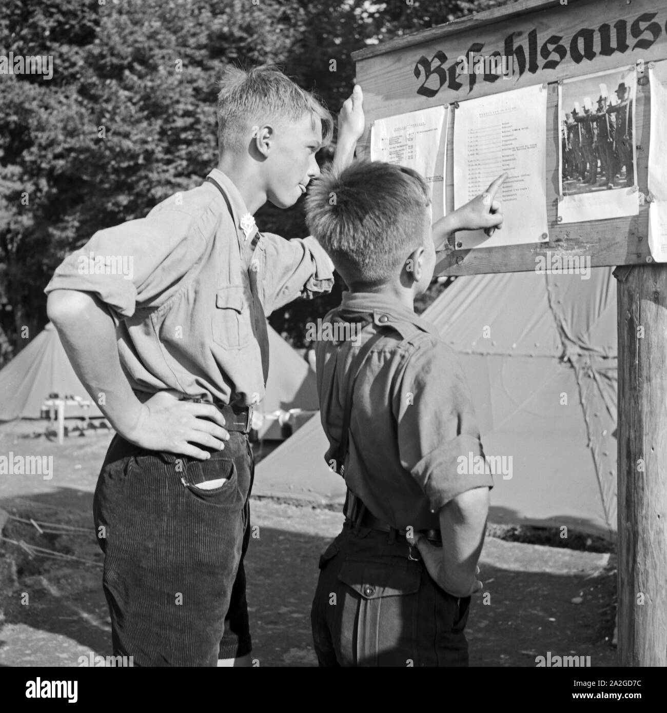 Zwei Hitlerjungen schulmeisterschaft sich den Tagesbefehl am Schwarzen Brett im Hiitlerjungend Lager ein, Österreich 1930er Jahre. Zwei Hitler Jugend lesen die Reihenfolge der Tag auf dem Aushang an der Hitler Jugend Camp, Österreich 1930. Stockfoto