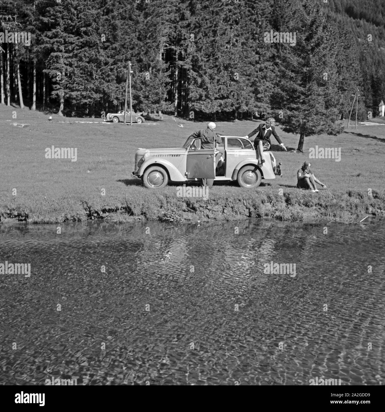 Drei junge Leute bei einer Rast am See auf Urlaubsfahrt im Opel Olympia in Österreich, 1930er Jahre. Drei junge Menschen, die auf ihrer Reise durch Österreich mit Opel Olympia, 1930er Jahre, Stockfoto