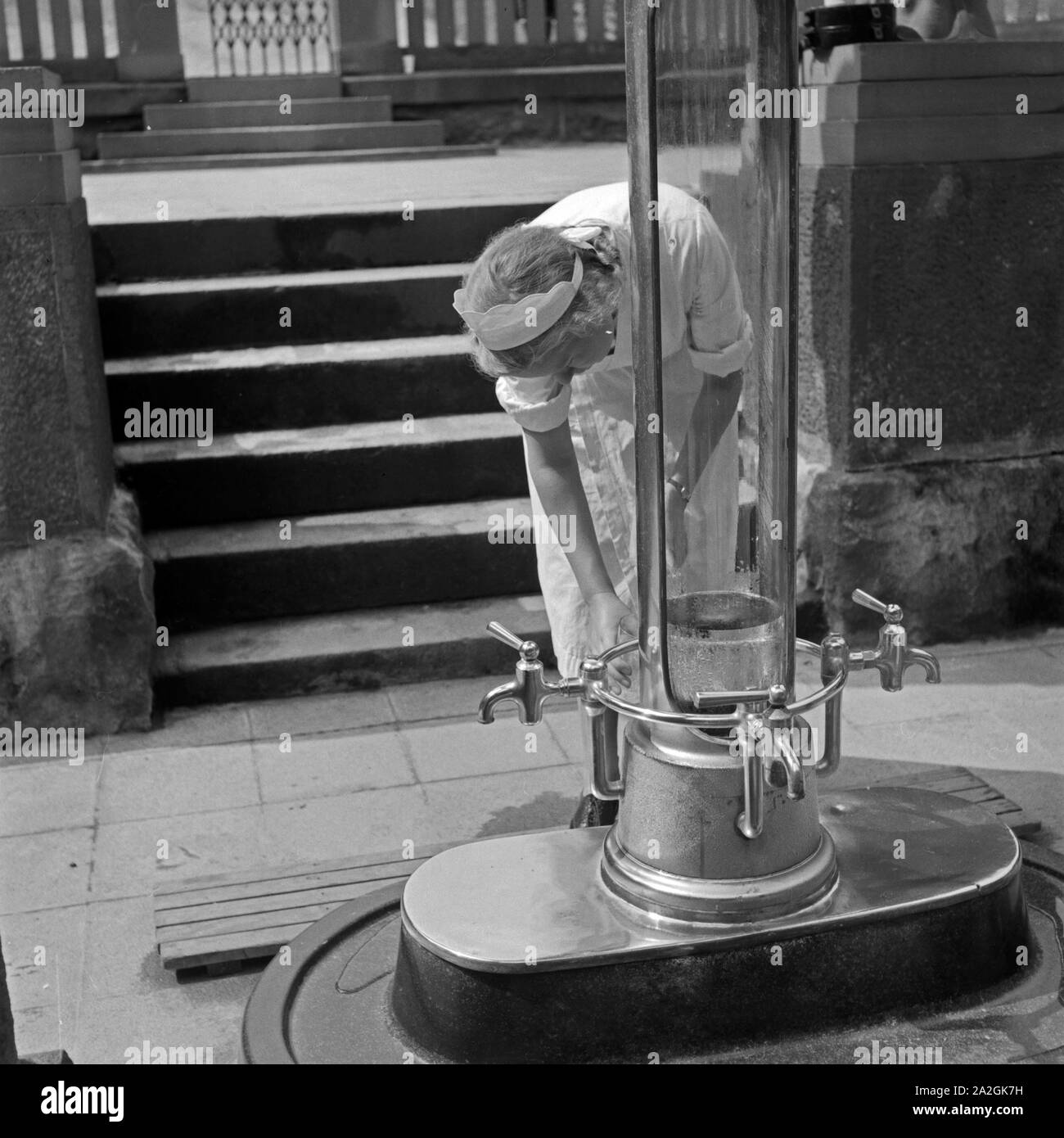 Eine Krankenschwester holt Kurgästen in Bad Homburg Wasser aus der Heilquelle, Deutschland 1930er Jahre. Eine Krankenschwester, die Wasser aus einer Heilquelle zu spa Gäste in Bad Homburg, Deutschland 1930. Stockfoto