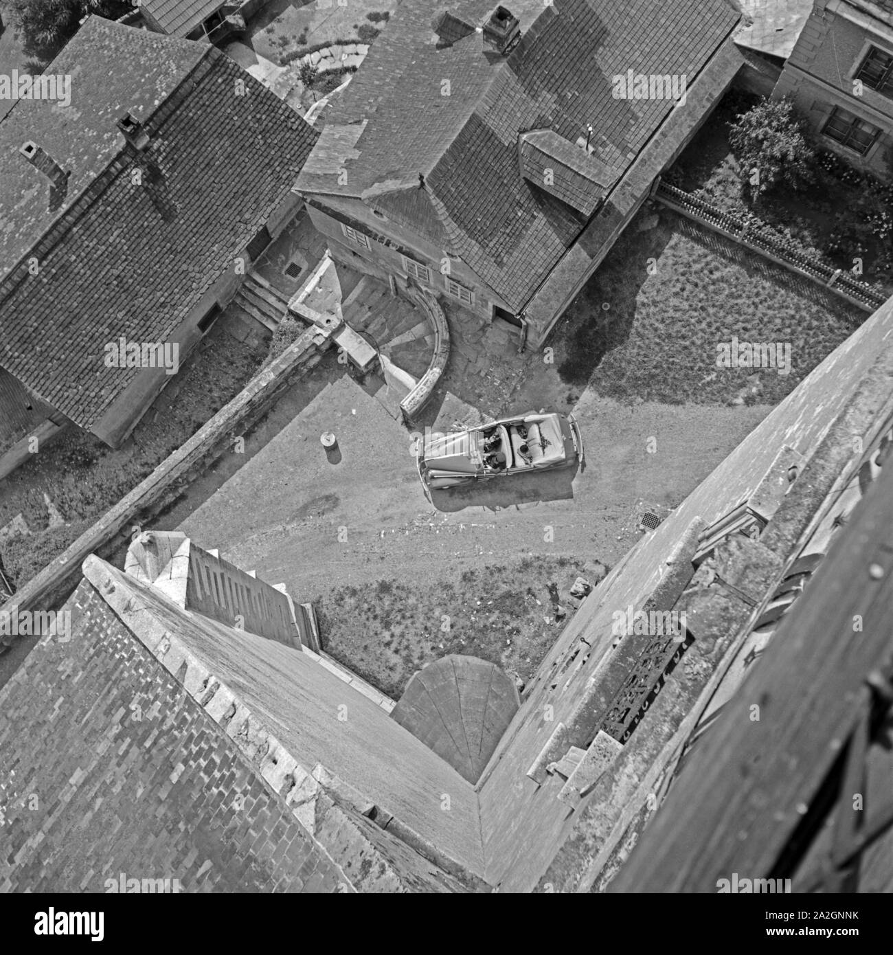 Blick von einem Kirchturm in ein durch ein Dorf fahrendes Opel Cabrio, Österreich 1930er Jahre. Luftaufnahme von einem Glockenturm ein Opel Cabrio, durch ein Dorf fahren, Österreich 1930. Stockfoto