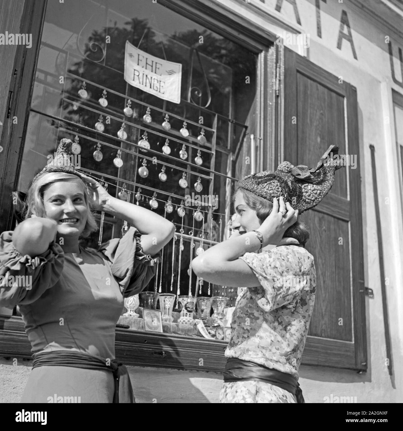 Zwei junge Frauen haben einen neuen Hut Referenzen und sehen Sie sich in der Spiegelung eines Schaufensters ein, Österreich 1930er Jahre. Zwei junge Frauen gekauft neue Hüte und im Spiegel eines shop Fenster überprüfen, Österreich 1930. Stockfoto