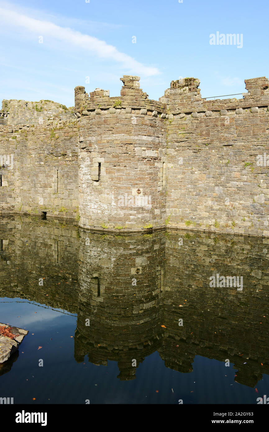 Eine der seitlichen Türme mit Reflexion in den Wassergraben in Beaumaris Castle auf Anglesey im Norden von Wales. Stockfoto