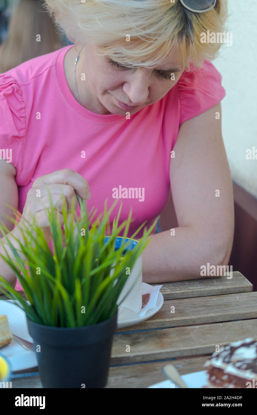 Eine Frau von 45-50 Jahre alt sitzt traurig in einem Café bei einer Tasse Kaffee Stockfoto