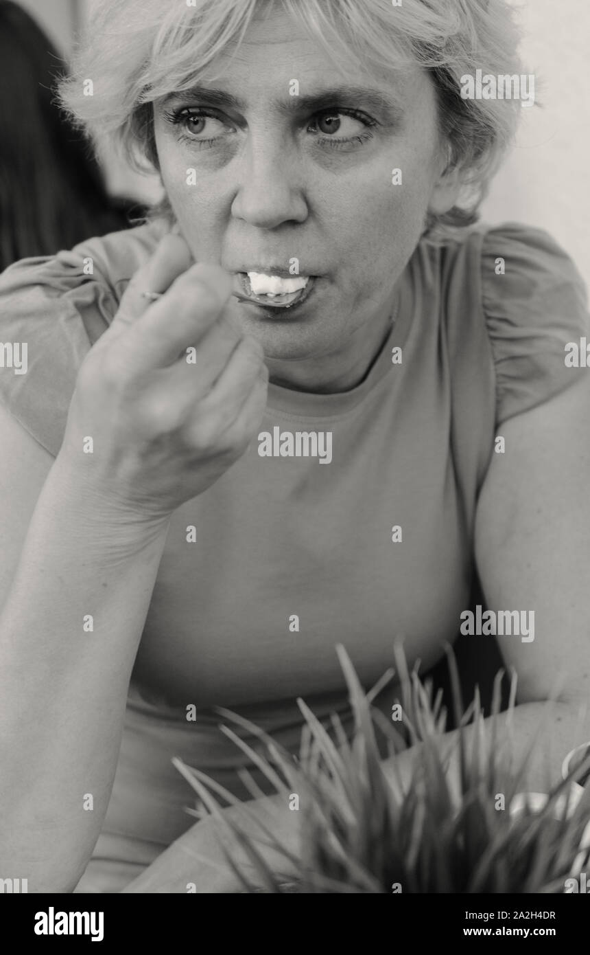 Eine Frau von 45-50 Jahre alt sitzt traurig in einem Café bei einer Tasse Kaffee Stockfoto