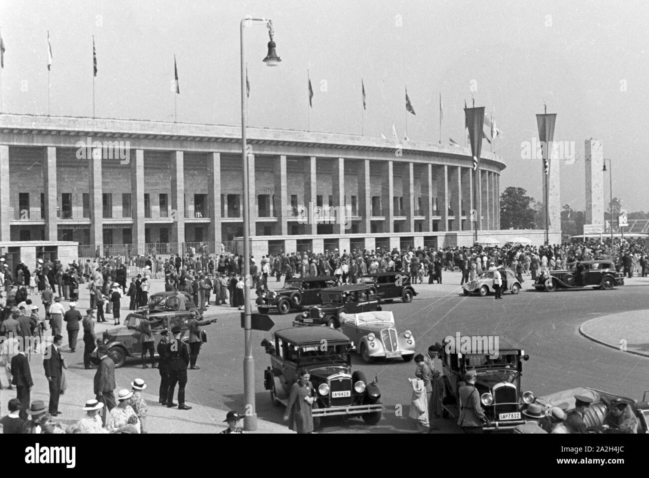 Eine Menschenmenge einer Straße mit Taxis vor dem Stadion in Berlin, Deutschland, 1930er Jahre. Masse an einer stark befahrenen Straße mit Taxis vor dem Olympiastadion Berlin, Deutschland 1930. Stockfoto