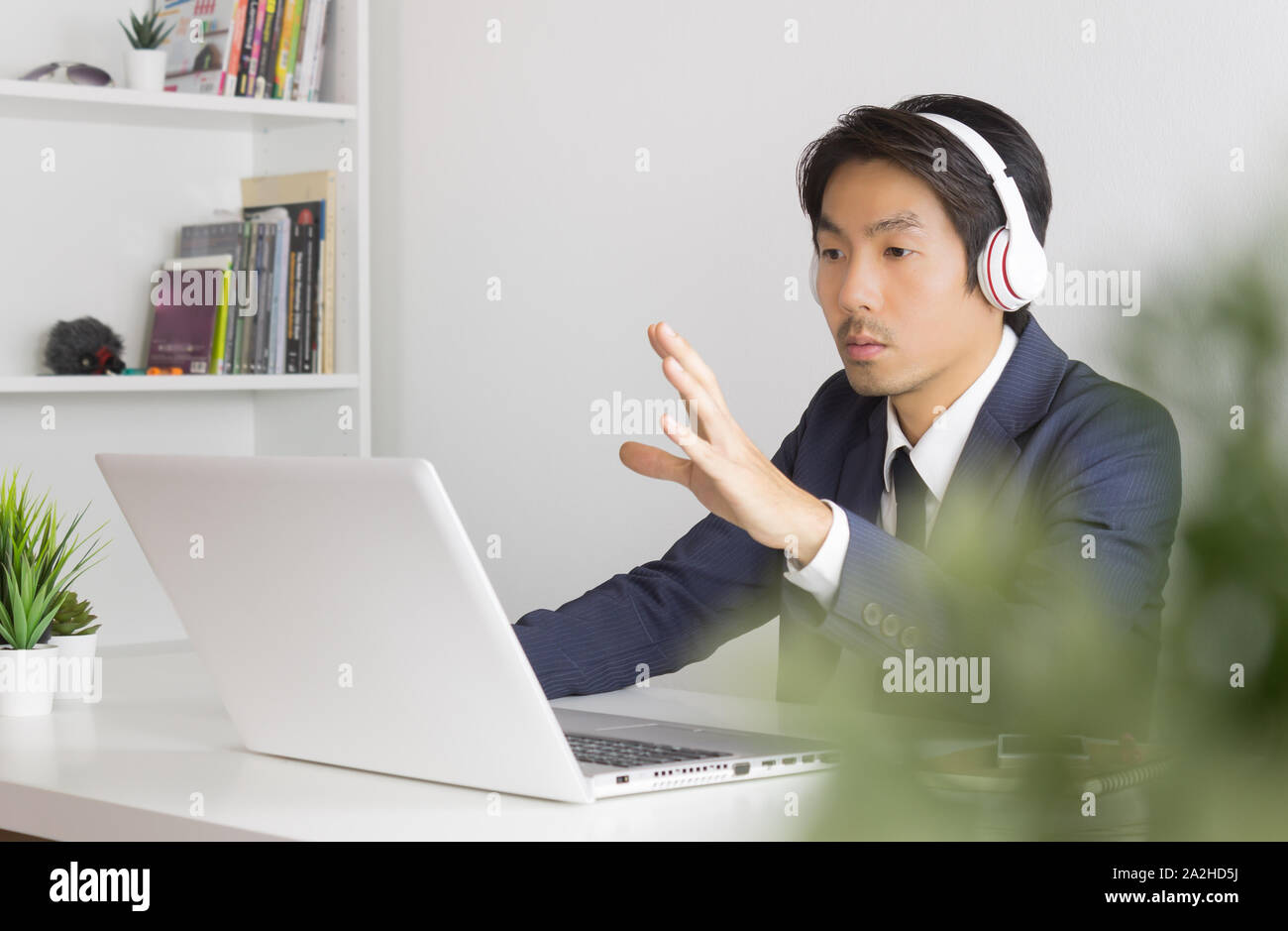 Asiatische Geschäftsmann oder asiatischen Berater in formalen blauen Anzug Reden und Schlagen Sie dem Kunden die auf dem Laptop Bildschirm im Büro. Consulting Services von profe Stockfoto