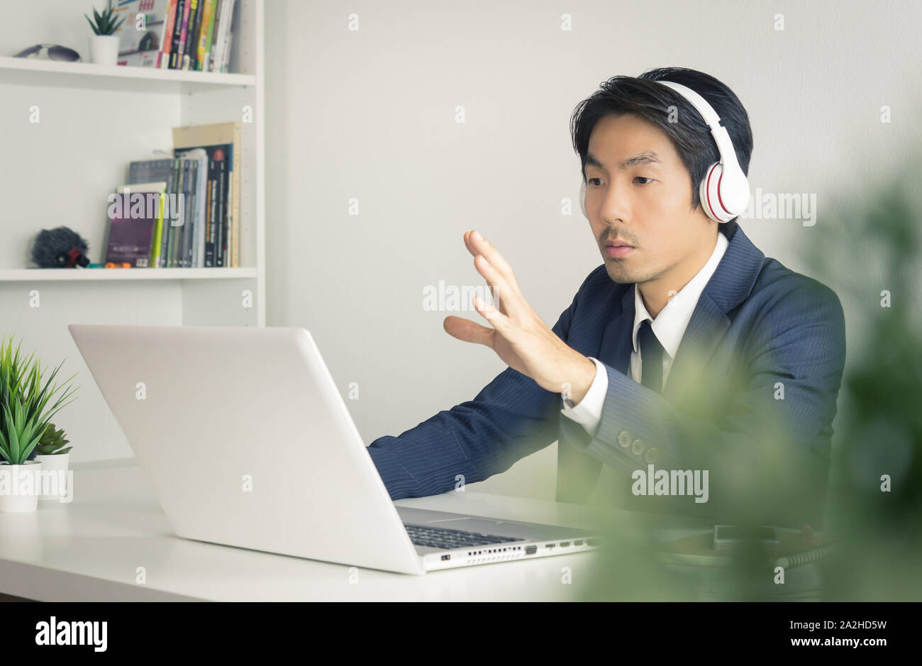 Asiatische Geschäftsmann oder asiatischen Berater in formalen blauen Anzug Reden und Schlagen Sie dem Kunden die auf dem Laptop Bildschirm im Büro. Consulting Services von profe Stockfoto
