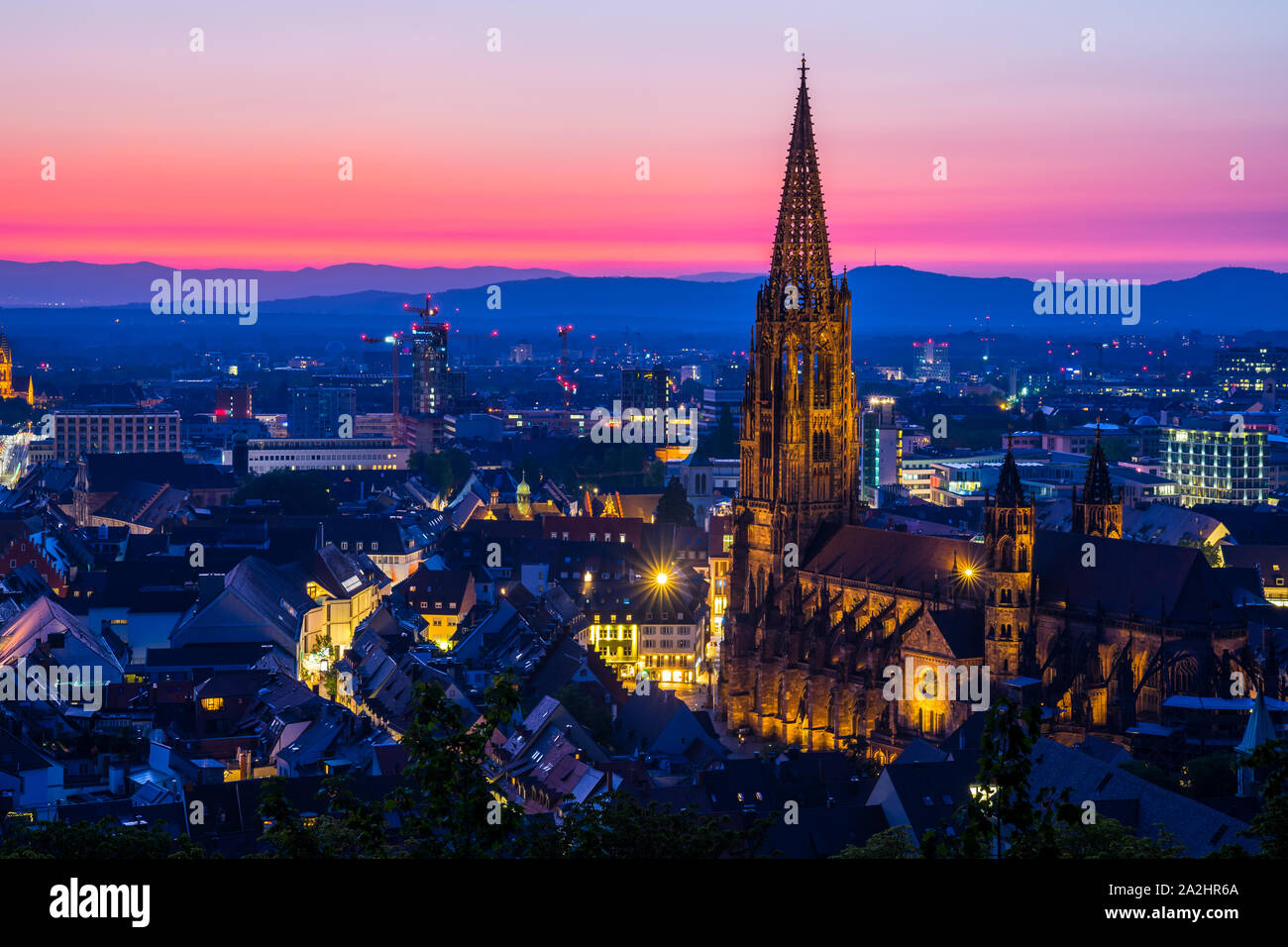 Deutschland, intensive rote Nachglimmen Himmel verzieren wunderschöne Skyline der Schwarzwald city Freiburg im Breisgau und berühmten beleuchtete Kirche Münster von Ni Stockfoto