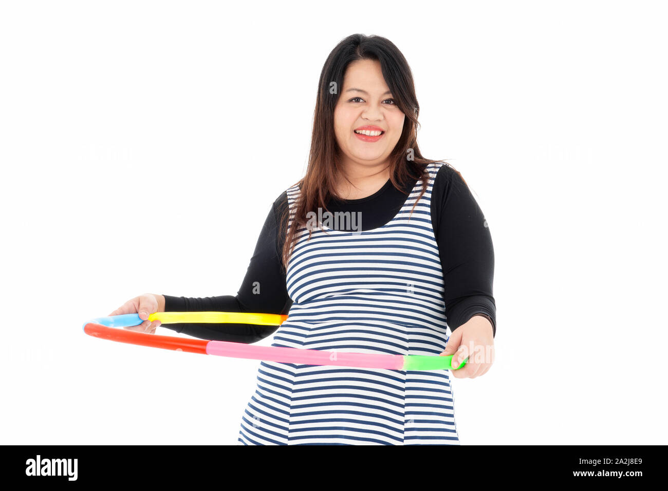 Fett junge schöne Frau ist die Ausübung von bunten hula - Hoop mit beiden Händen. Sie lächelt und genießt Schlusses Gewicht für Ihre gute Gesundheit. Isoliert auf ein Stockfoto