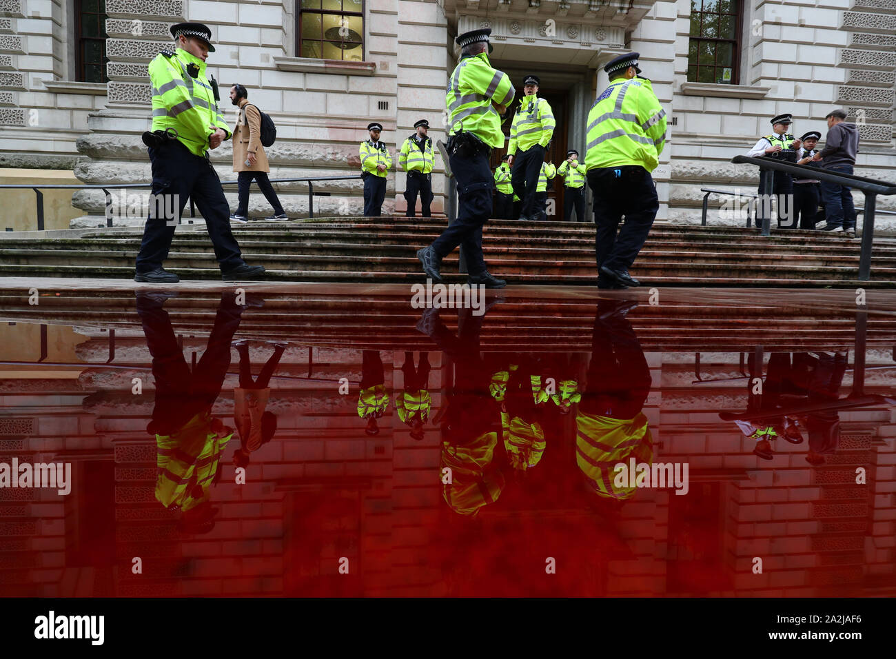 Polizisten außerhalb des Treasury Gebäude in Westminster, wo Aussterben Rebellion Mitkämpfer 1.800 Liter fake Blut von einem Feuerwehrauto gesprüht haben. Stockfoto