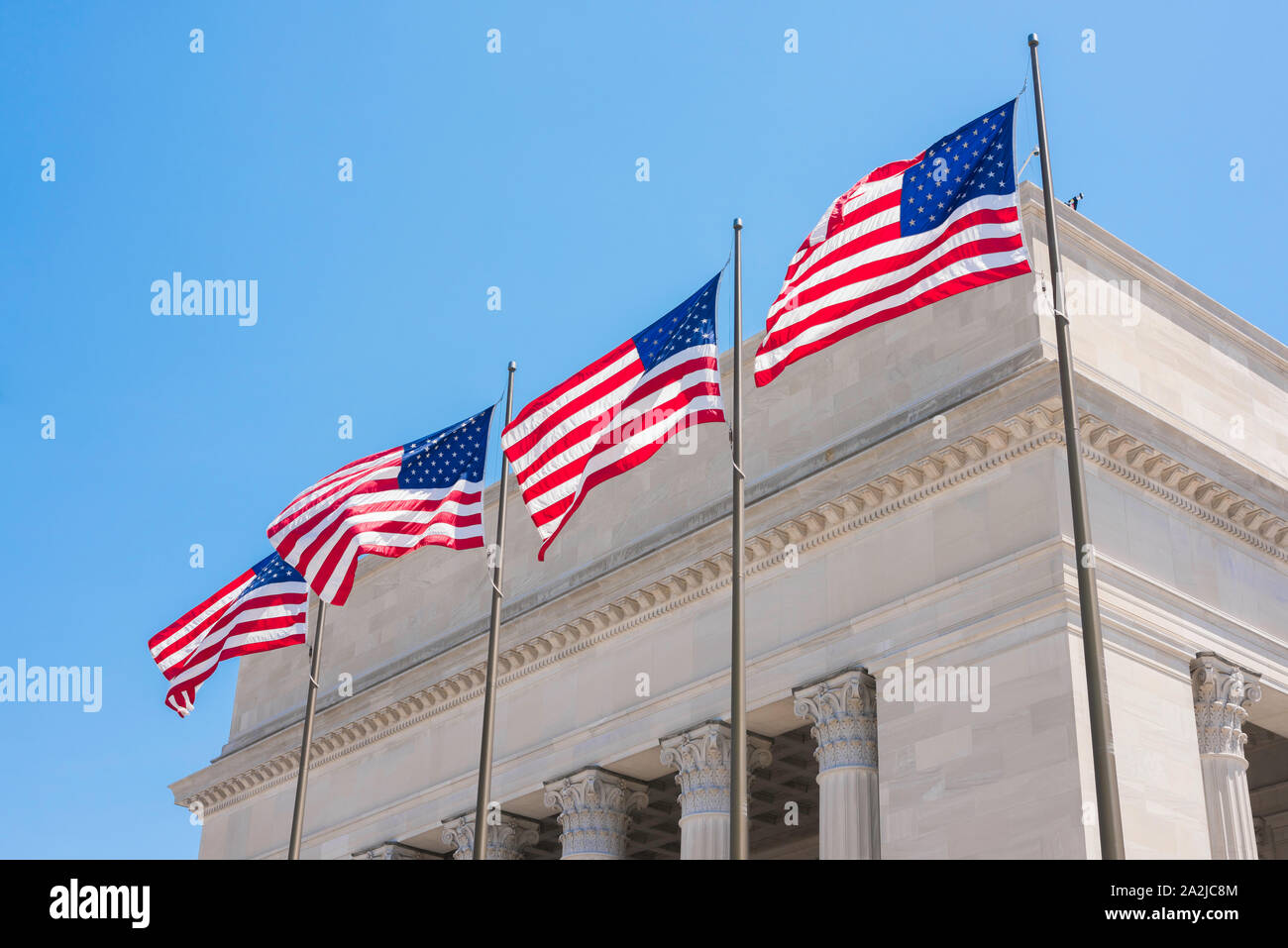 US-Justiz, Blick auf vier US-Nationalflaggen vor einem Gebäude des amerikanischen Gerichtsgebäudes im neoklassizistischen Stil. Stockfoto
