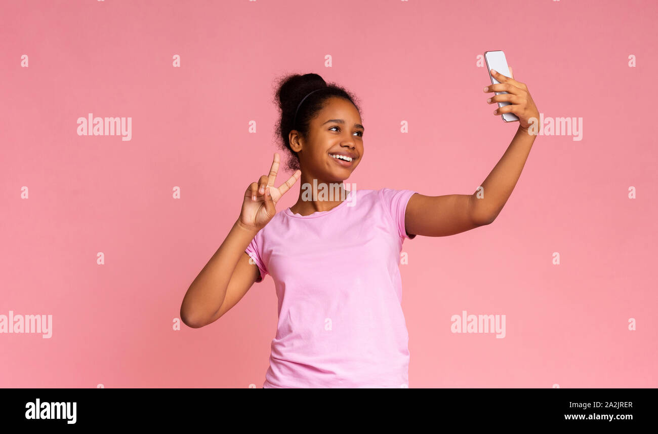 Fröhliche afrikanisches Mädchen machen selfie auf dem Smartphone, Frieden Geste Stockfoto