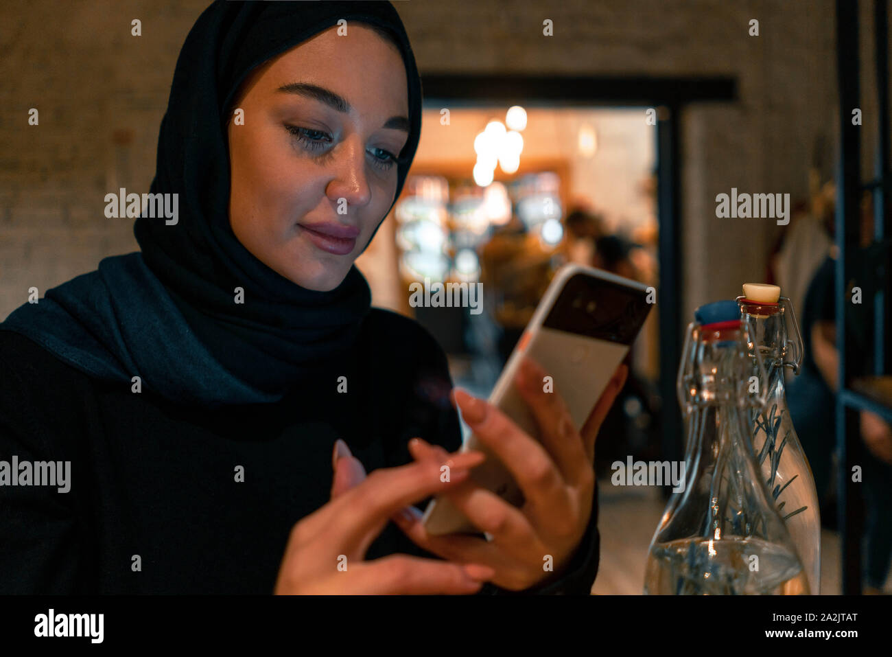 Muslimische Frau im Cafe Einkaufen online mit modernen Handy. Konzept der Lebens voller Leben mit modernen Haltung von tolerierbaren Gesellschaft. Stockfoto