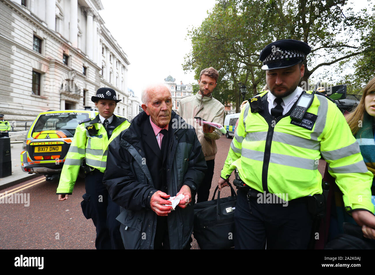 Demonstrant Phil Kingston ist weg von der Polizei außerhalb der Treasury Gebäude in Westminster, wo Aussterben Rebellion gesprüht haben 1.800 Liter Fake Blood geführt. Stockfoto