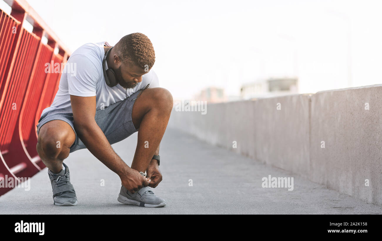 Afro Kerl die Kontrolle über seine Schnürsenkel auf Brücke Stockfoto