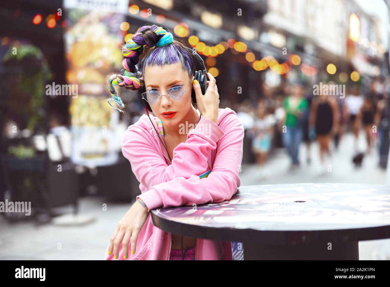 Cool funky junge Frau mit trendigen Avantgarde look Musik hören über Kopfhörer im Freien Stockfoto