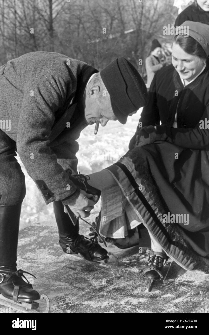 Mein Mann hilft einer Frau beim Anschnallen von Schlittschuhkufen im Spreewald, Deutschland, 1930er Jahre. Ein Mann, eine Frau auf schlittschuh Läufer im Spreewald, Deutschland 1930. Stockfoto