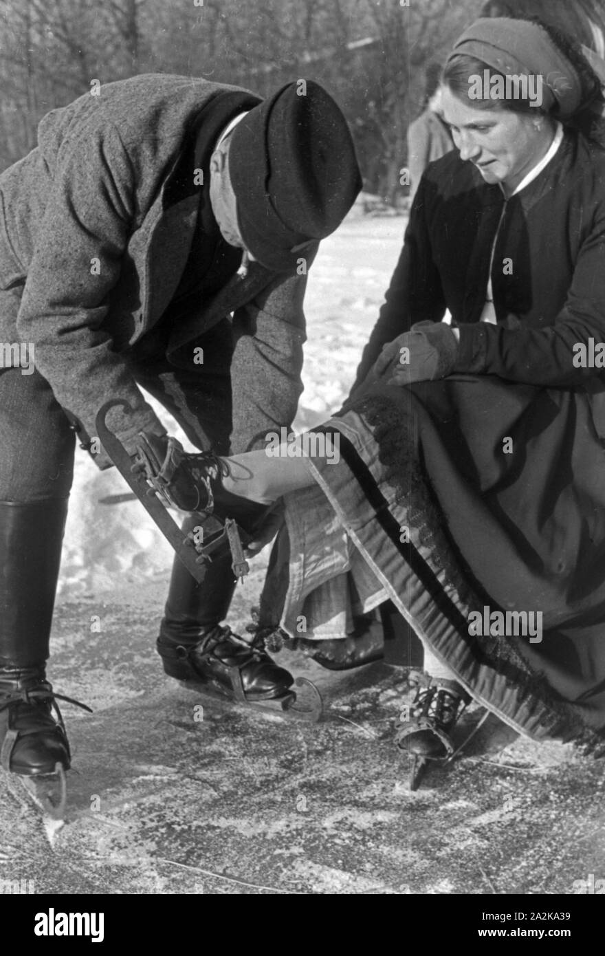 Mein Mann hilft einer Frau beim Anschnallen von Schlittschuhkufen im Spreewald, Deutschland, 1930er Jahre. Ein Mann, eine Frau auf schlittschuh Läufer im Spreewald, Deutschland 1930. Stockfoto