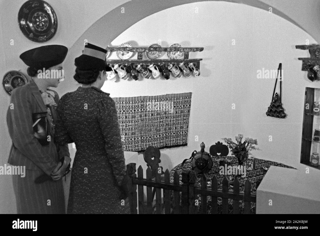Zwei Frauen vor dem mit Kunsthandwerk aus der Kunstgeschichte auf der Messe Leipzig, Deutschland 1940er Jahre stehen. Zwei Frauen am Stand mit Kunst und Kunsthandwerk der Sowjetunion auf der Leipziger Messe, Deutschland 1940. Stockfoto