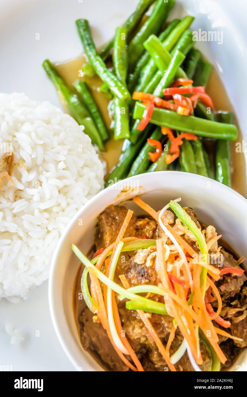 Beef Rendang mit Julienned Karotten oben serviert, gebratene Bohnen und weißer Reis Stockfoto