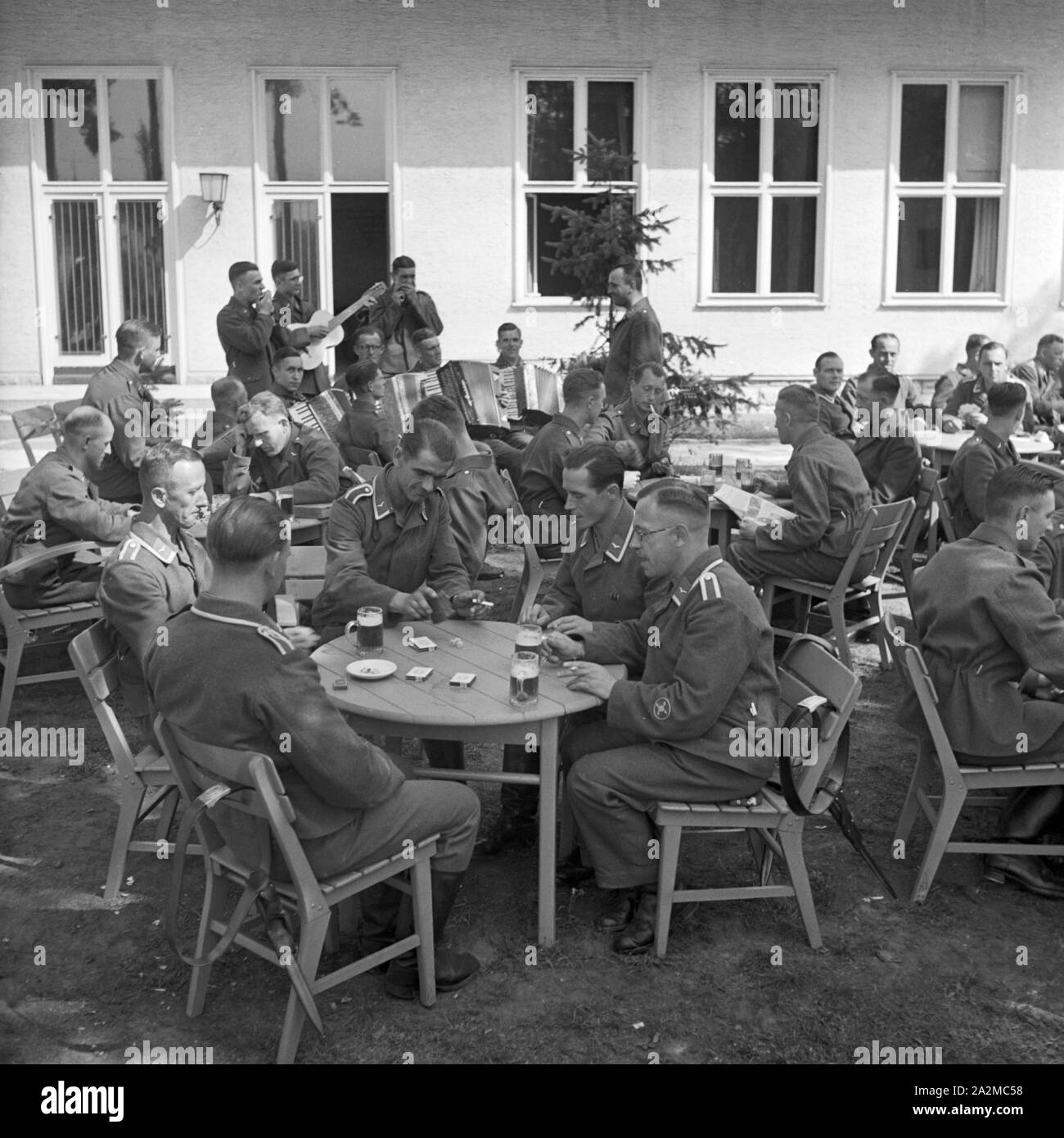 Original-Bildunterschrift: frohes Beisammensein nach dem Dienst in einem Fliegerhorst. Eine Kapelle sorgt für die richtige Stimmung, Deutschland 1940er Jahre. Zusammen nach Aufgabe an eine Luftwaffe Baracke mit einem Combo spielen Musik, Deutschland 1940 s kommen. Stockfoto