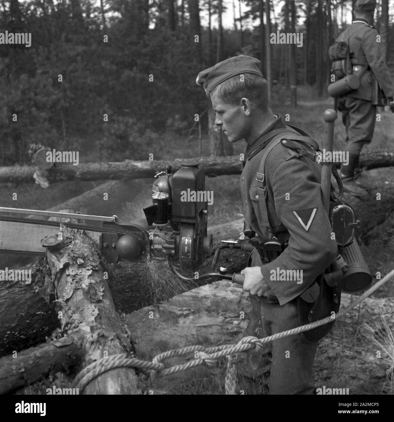 Original - Bildunterschrift: Pionierarbeit mit der Kraftsäge, Deutschland 1940er Jahre. Soldat der militärischen engineering mit einer Kettensäge, Deutschland 1940. Stockfoto