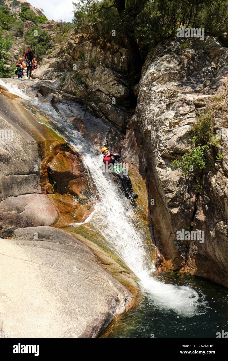 Touristen auf eine natürliche Wasserrutsche canyoning den Cascades de Purcaraccia, Zoza in das Bavella Gebirge Korsika Frankreich - Korsika Abenteuer Stockfoto