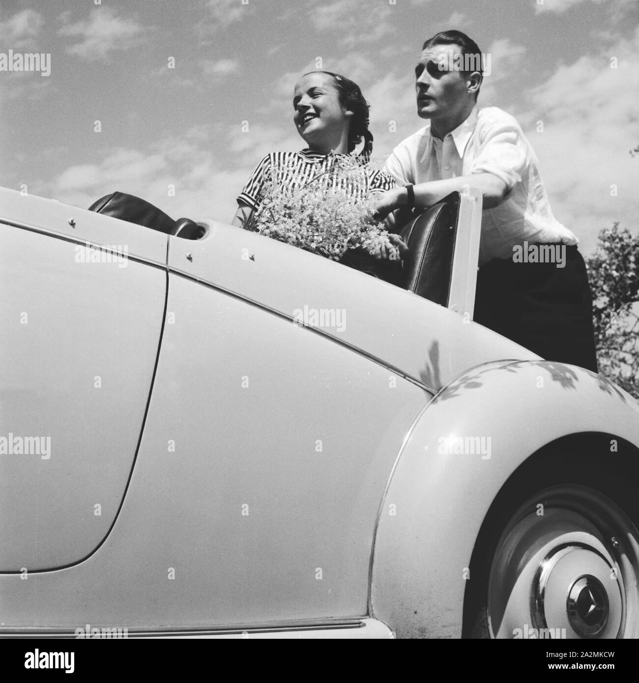 Ein Mann und eine Frau bei einer Pause eine ihrem Mercedes Benz Cabrio, Deutschland 1930er Jahre. Ein Mann und eine Frau, die einen Bruch in der Nähe des Mercedes Benz Cabrio, Deutschland 1930. Stockfoto