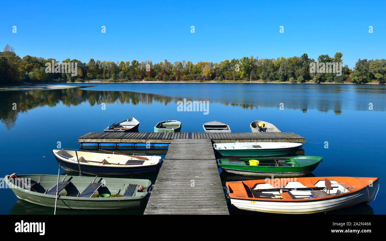 Herbst Landschaft. Ein See, ein Boot Brücke und einige Boote mit gelben und grünen Bäumen im Hintergrund. 68782 Bruehl, Baden-Württemberg, Deutschland. Stockfoto