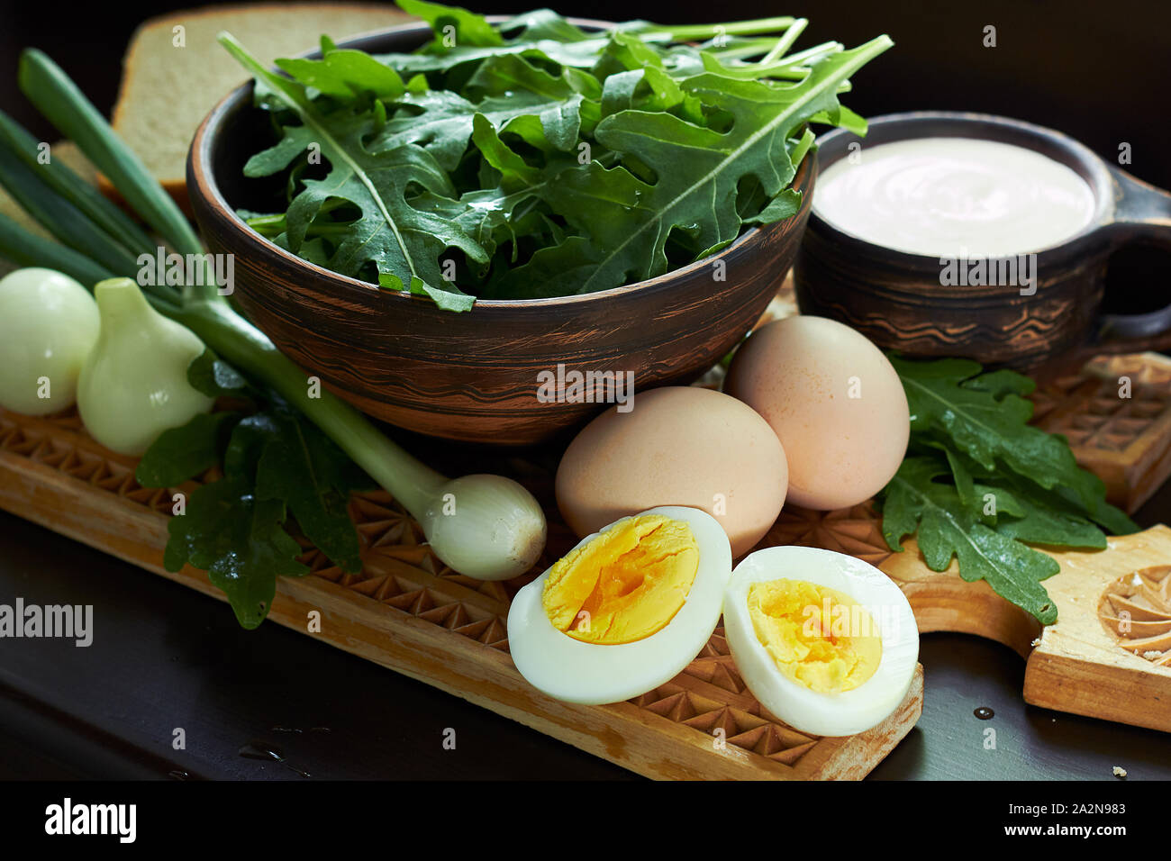 Rucola oder Rucola mit gekochtem Ei, grüne Zwiebeln, Brot und saure Sahne so einfach Land Essen auf rustikalen hölzernen Schneidebrett, Nahaufnahme, vegetarische f Stockfoto