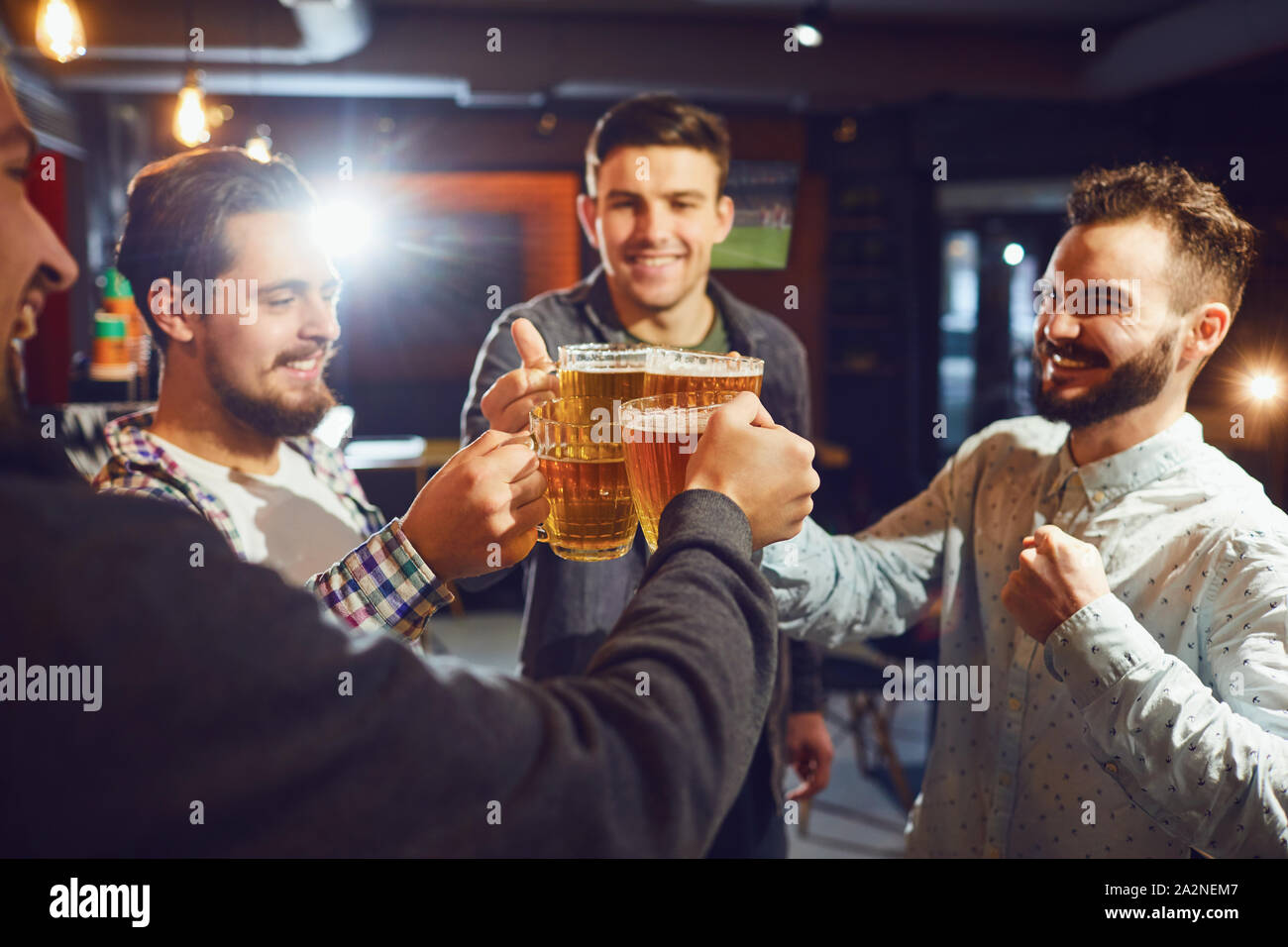 Freunde klirren Bierkrüge in bar Stockfoto