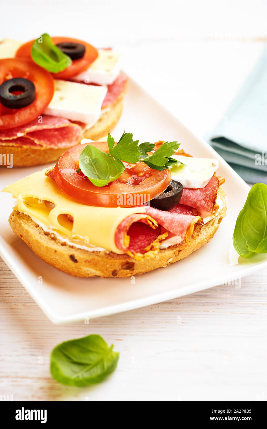 Belegte Brötchen mit Salami, Käse, Tomaten, Camembert, schwarze Oliven ...