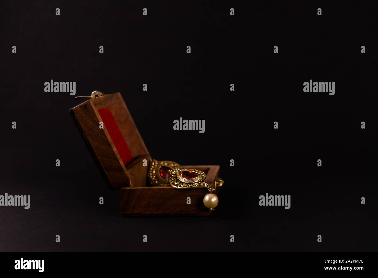 Golden Earing in Holz- Geschenkbox auf schwarzen Hintergrund. Schmuck Geschenk Konzept Stockfoto