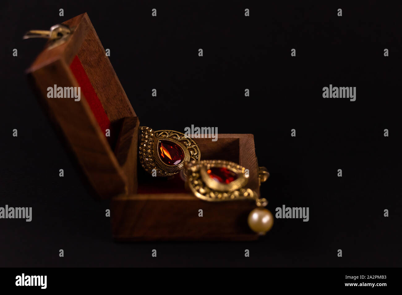 Goldene Ohrringe in Holz- Geschenkbox auf dunklem Hintergrund. Zipfelbildung Geschenk Konzept Stockfoto